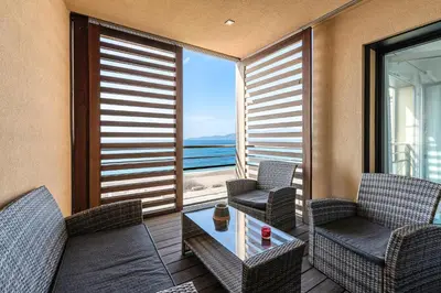 a balcony with chairs and a table with a view of the ocean at Agosta Bella - Appt en face de la plage dAgosta in Albitreccia