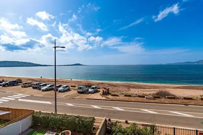 a view of the beach and a road with cars parked at Agosta Bella - Appt en face de la plage dAgosta in Albitreccia