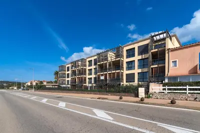 an empty street in front of an apartment building at Agosta Bella - Appt en face de la plage dAgosta in Albitreccia
