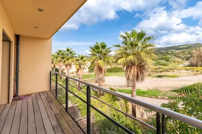 a balcony with a view of palm trees at Agosta Bella - Appt en face de la plage dAgosta in Albitreccia