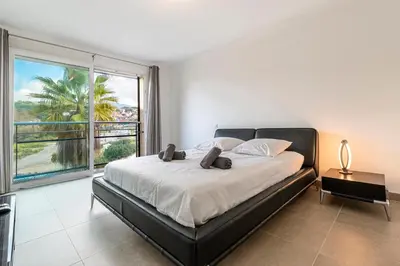 a bedroom with a large bed and a large window at Agosta Bella - Appt en face de la plage dAgosta in Albitreccia