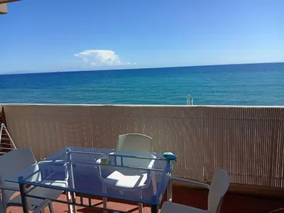 a blue table and chairs on a balcony with the ocean at Studio vue mer bord de plage in San-Nicolao