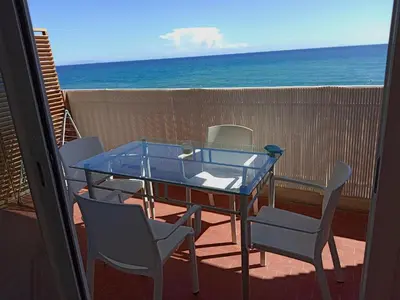 a glass table and chairs on a balcony with the ocean at Studio vue mer bord de plage in San-Nicolao