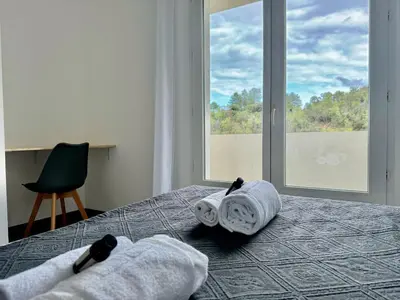 a bedroom with towels on a bed with a window at Villa Mare è Machja avec piscine et vue mer in Sari Solenzara