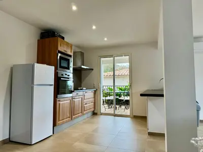 a kitchen with a white refrigerator and a table at Appartement Mare è Machja avec piscine et vue mer in Sari Solenzara