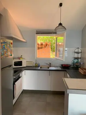 a kitchen with white cabinets and a sink and a window at Maison Corallo splendide vue mer in Porto-Vecchio