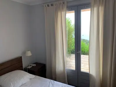 a bedroom with a bed and a sliding glass door at Maison Corallo splendide vue mer in Porto-Vecchio