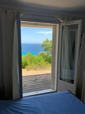 a bedroom with a window with a view of the ocean at Maison Corallo splendide vue mer in Porto-Vecchio