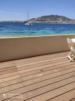 a deck with a view of the ocean and a boat at Residence CORSE AZUR AJACCIO in Ajaccio