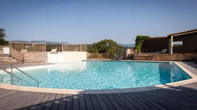 a large swimming pool with a wooden deck at Résidence Santa Giulia Park 1 avec piscine à proximité des plages in Porto-Vecchio