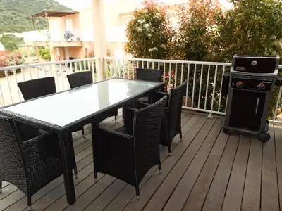 a table and chairs on a deck with a grill at Résidence Santa Giulia Park 1 avec piscine à proximité des plages in Porto-Vecchio