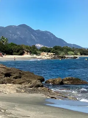 a beach with people walking on the sand and water at COCON AUX SENTEURS de CORSE et VUE EXCEPTIONNELLE in Linguizzetta