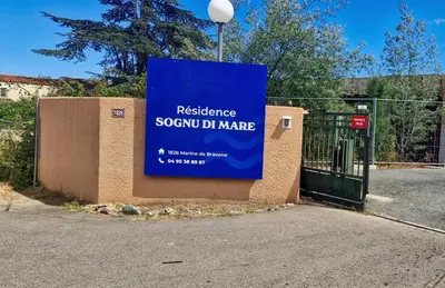 a sign on the side of a building with a gate at COCON AUX SENTEURS de CORSE et VUE EXCEPTIONNELLE in Linguizzetta