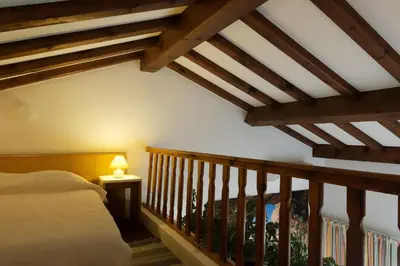 a bedroom with a bed and a staircase with wooden beams at COCON AUX SENTEURS de CORSE et VUE EXCEPTIONNELLE in Linguizzetta