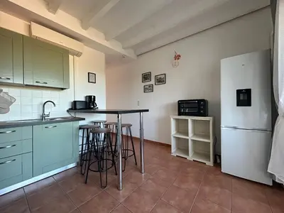 a kitchen with a table and a refrigerator at Appartement dans résidence avec piscine et plage privées in San-Nicolao