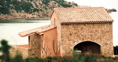 a stone building with a door in front of a lake at Résidence Fioravanti Villas Valinco in Tizzano
