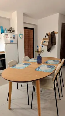 a dining room table with chairs and a kitchen at Appart 70m2 avec loggia, piscine à débordement vue mer in Pianottoli-Caldarello