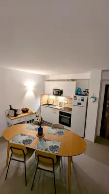 a kitchen with a table and two chairs and a table and a kitchen at Appart 70m2 avec loggia, piscine à débordement vue mer in Pianottoli-Caldarello