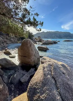 a rock sitting on a beach next to the water at Appart 70m2 avec loggia, piscine à débordement vue mer in Pianottoli-Caldarello