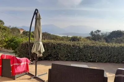 an umbrella sitting next to a table and a chair at Appartement T2 Belvedere campomoro in Portigliolo