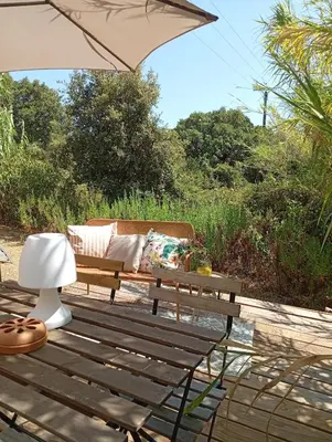 a wooden bench sitting on a wooden deck with an umbrella at Résidence A Casetta in Monacia-dʼAullène