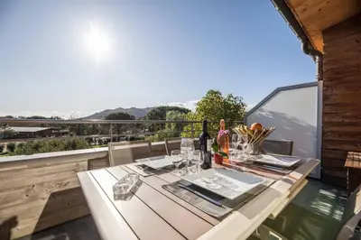 a table with wine bottles and glasses on a balcony at Appartement 4* piscine et plage à pied in Porto-Vecchio