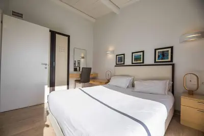 a bedroom with a large white bed and a desk at Appartement 4* piscine et plage à pied in Porto-Vecchio