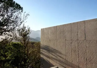 a large concrete wall with trees and mountains in the background at Villa d'architecte in Sotta