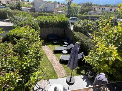 a garden with benches and an umbrella in the grass at Maison bord de mer in Poggio-Mezzana