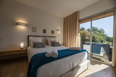 a bedroom with a large bed and a large window at Appartement 4 étoiles piscine et plage à pied in Porto-Vecchio