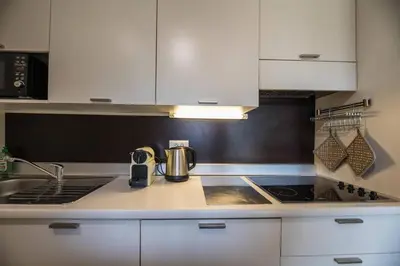 a kitchen with white cabinets and a stove top oven at Appartement 4 étoiles piscine et plage à pied in Porto-Vecchio