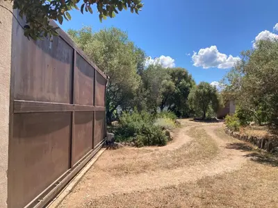 a fence in a yard with trees in the background at Villa élégante à Sagone avec piscine privée et vue sur la mer in Sagone