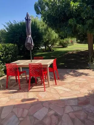 a table and chairs with an umbrella on a patio at Location à Porto Vecchio in Porto-Vecchio