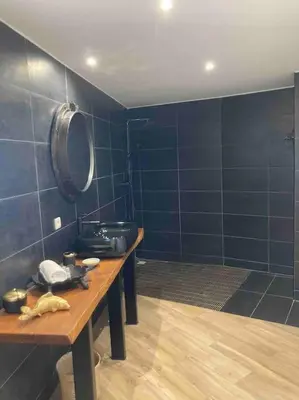 a bathroom with blue tiled walls and a wooden table at Location à Porto Vecchio in Porto-Vecchio