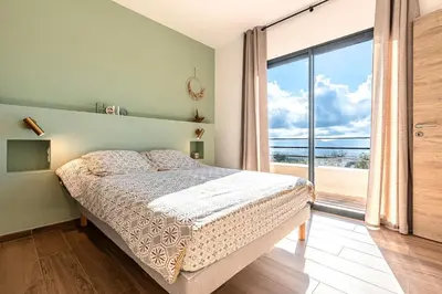 a bedroom with a bed and a large window at Maison Altea - Maison climatisée in Figari