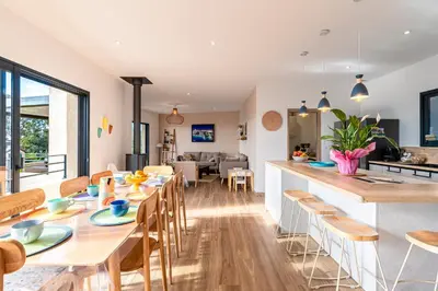 a kitchen and dining room with wooden tables and chairs at Maison Altea - Maison climatisée in Figari