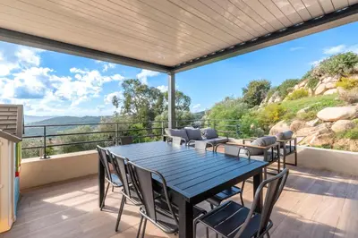 a dining room with a table and chairs on a balcony at Maison Altea - Maison climatisée in Figari