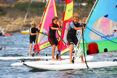 a group of children on sailboards on the water at Village Naturiste La Chiappa in Porto-Vecchio