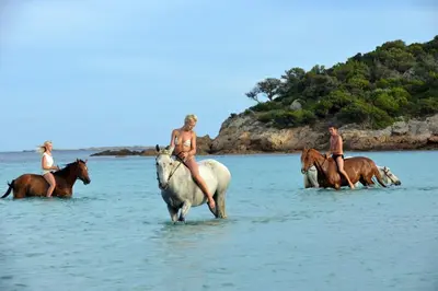 a group of people riding horses in the water at Village Naturiste La Chiappa in Porto-Vecchio