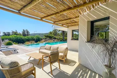 a patio with a couch and chairs and a pool at Villa San Ciprianu Mare Di Lecci in Lecci