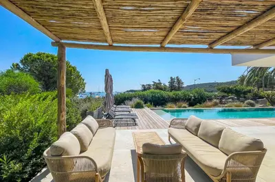 a patio with a couch and chairs and a pool at Villa San Ciprianu Mare Di Lecci in Lecci