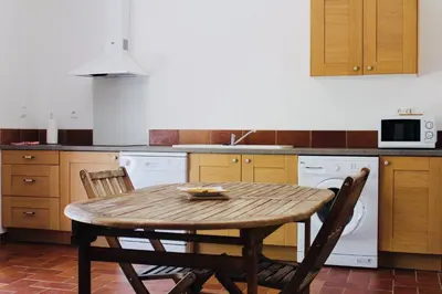 a kitchen with a wooden table and two chairs at A FATA DI L'ORTOLO gîtes à la ferme in Sartène