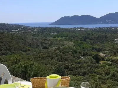 a table with chairs and a view of the water at La Tour dans haut de villa in Porto-Vecchio