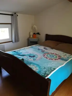 a bed in a bedroom with a blue blanket on it at La Tour dans haut de villa in Porto-Vecchio