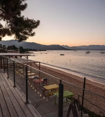 a wooden deck with a picnic table on the beach at Hotel L'Escale in Porto Pollo