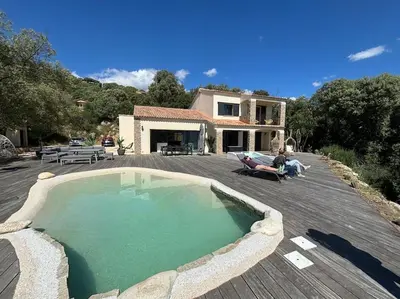 a house with a large swimming pool on a wooden deck at Casa Nostra in Olmeto