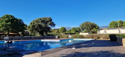 a swimming pool in a park with trees in the background at Eden Cala Rossa appartement 3 chambres et grande terrasse dans résidence hotelière Fiori di Cala Rossa à Lecci in Lecci