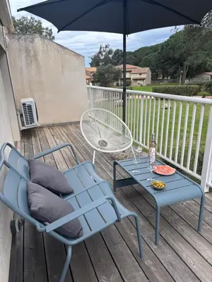 a blue table with chairs and an umbrella on a deck at Eden Cala Rossa appartement 3 chambres et grande terrasse dans résidence hotelière Fiori di Cala Rossa à Lecci in Lecci