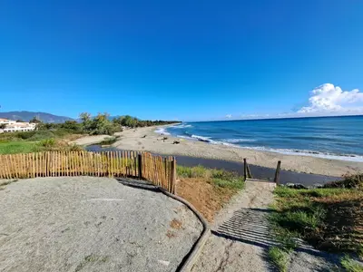 a beach with a wooden fence next to the ocean at Appartement avec piscine à 2 pas de la plage in Linguizzetta