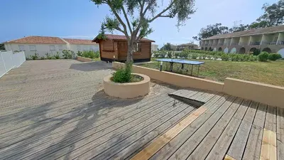 a wooden deck with a tree and a building at Appartement avec piscine à 2 pas de la plage in Linguizzetta